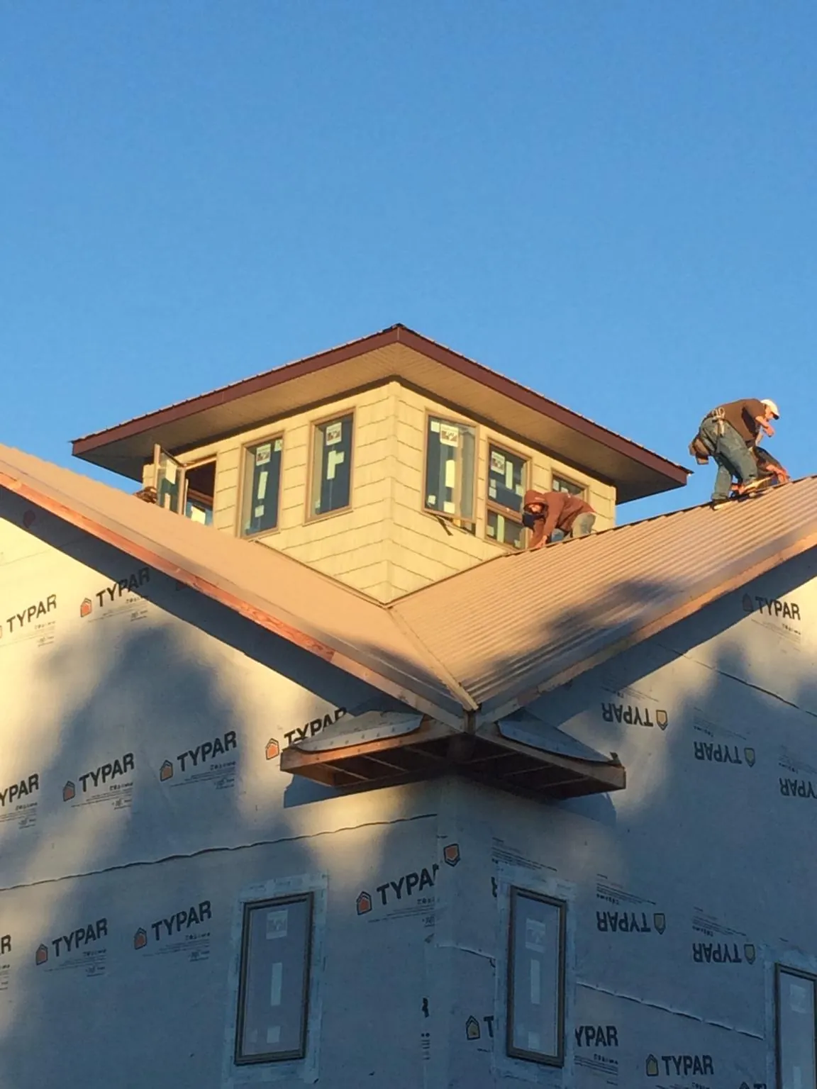 Roofers working around a rooftop cupola on a new metal roof at sunset — Roof Waterproofing in Rotonda West by Roofing Brothers